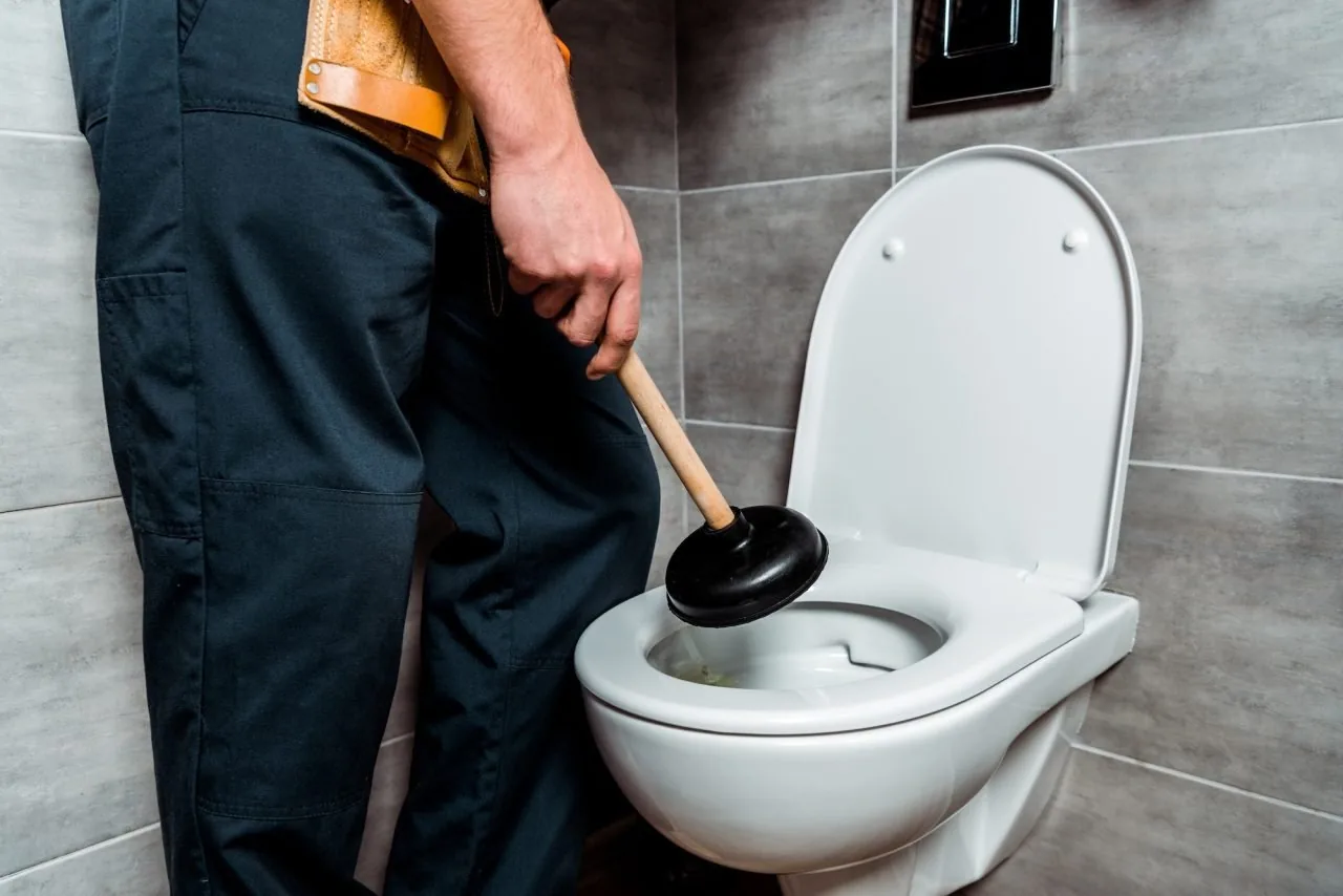 Plumber using a plunger to unclog a toilet